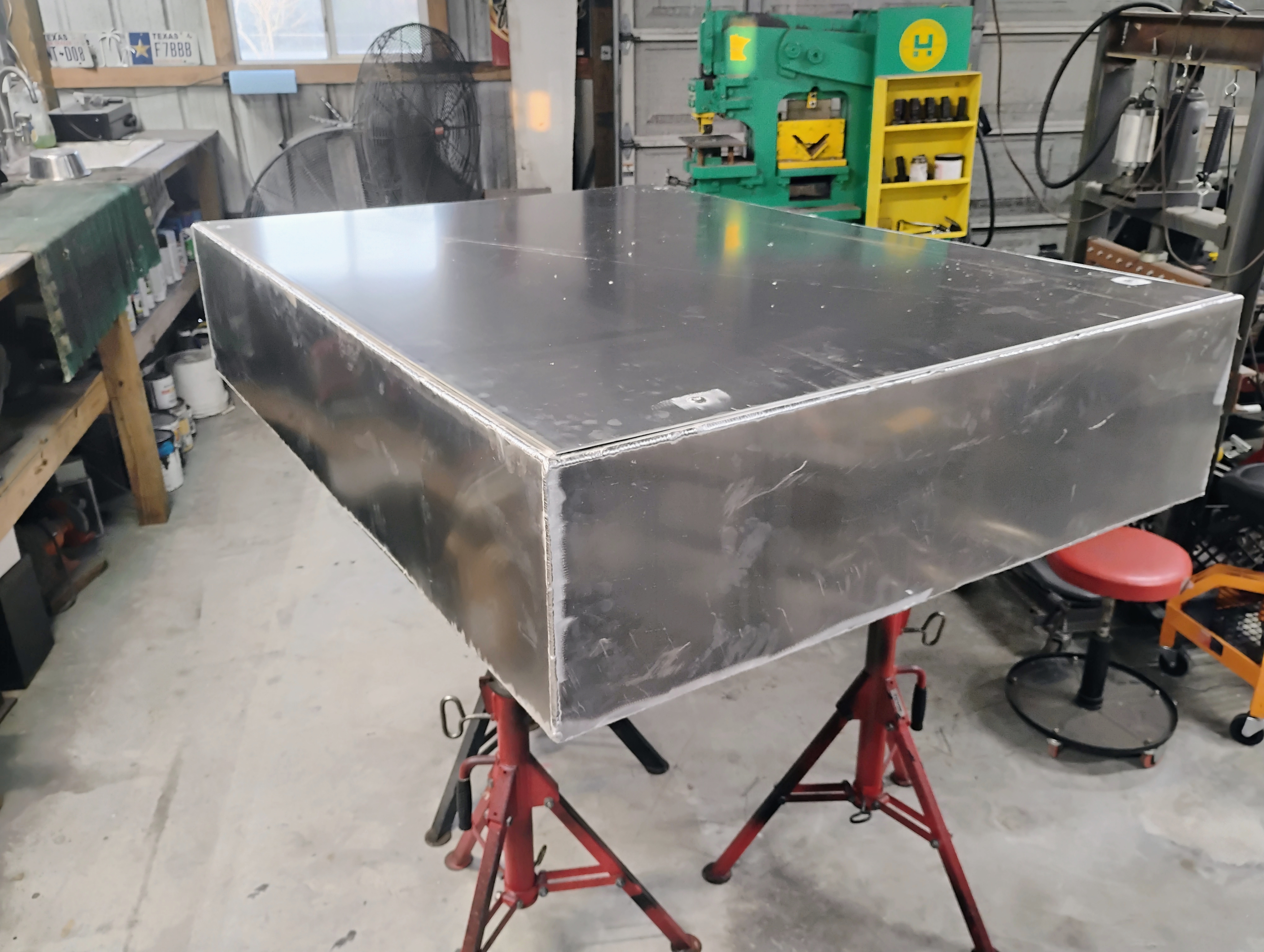 Custom stainless rectangular tank outer shell on jack stands in the shop