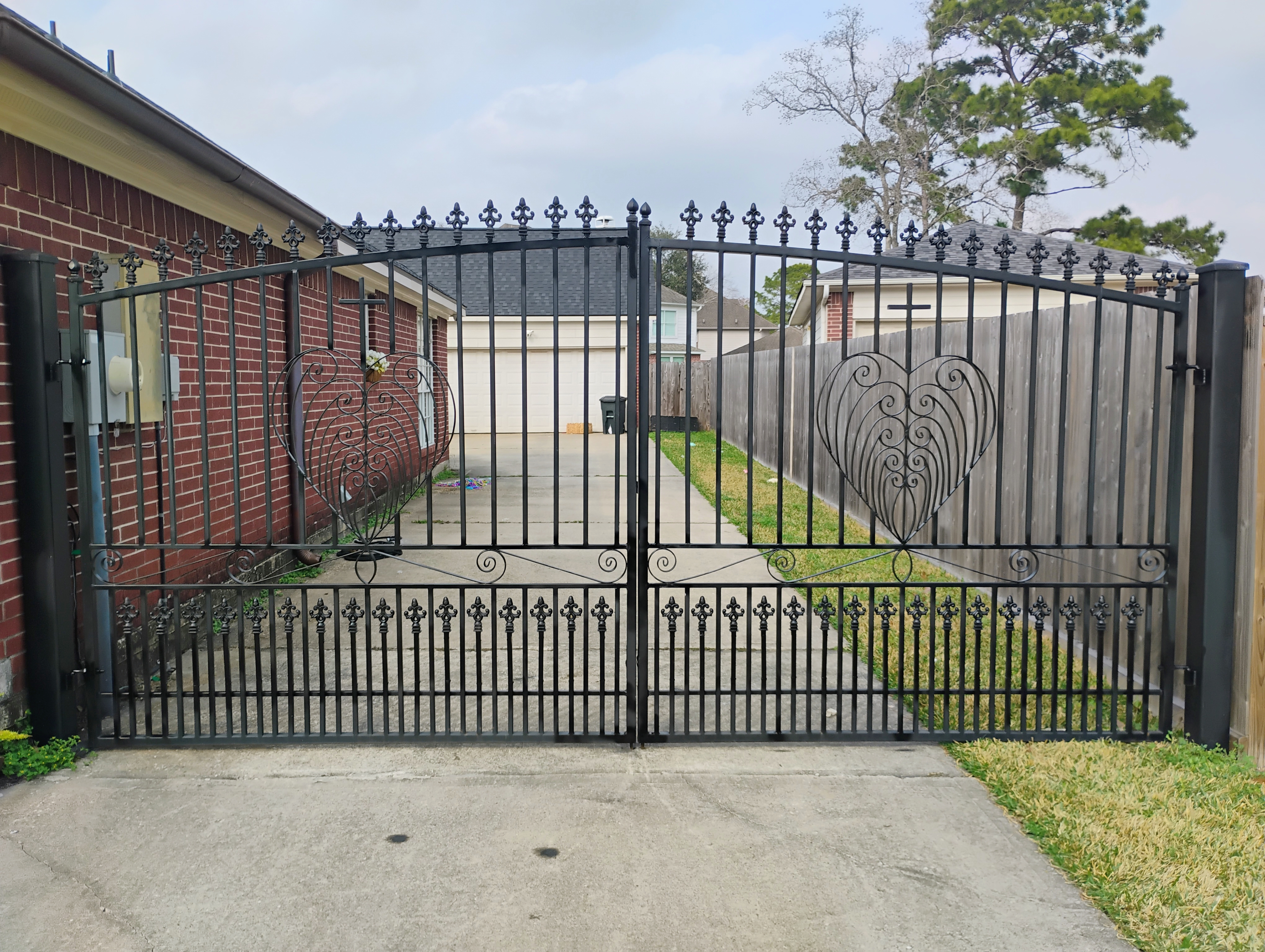 Custom black double driveway gate with heart scrollwork inserts, front view